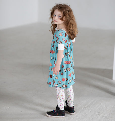 A young girl looking back at the camera in a colorful donut dress