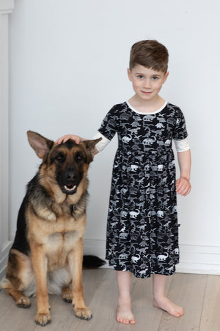 A kid wears a dinosaur dress while petting their dog