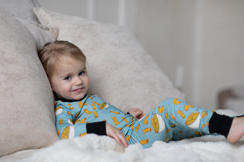 a child lounges in mac and cheese bamboo 2 piece pajamas