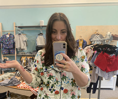 A woman uses the mirror to take a picture of herself wearing cute colorful floral pajamas.