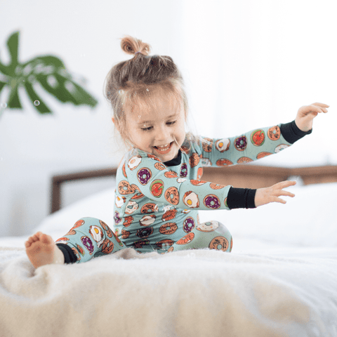 a child wearing bold, bright bamboo pajamas featuring bagels