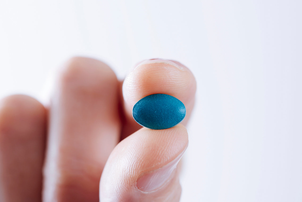 A man holding a blue viagra pill
