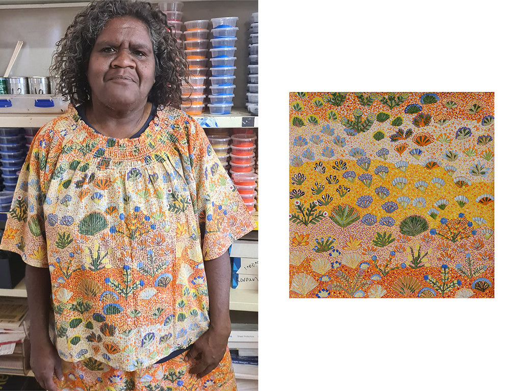 A photo of First Nations artist Julieanne Ngwarraye facing the camera wearing a top with her 'Desert Flower' artwork printed on it. To the left of the photo is an image of the entire Desert Flower artwork which depicts rocks and native plants and flowers. The colours are orange, yellow, green, purple, blue and white. There are different horizontal sections of the artwork from the top to the bottom of the page.