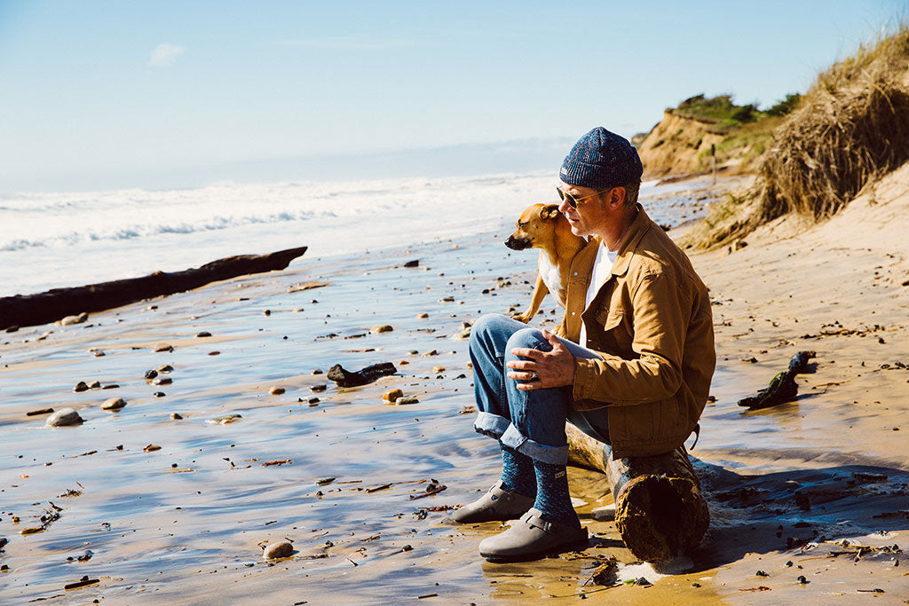 Man with his dog on the beach wearing Druthers and SALT.