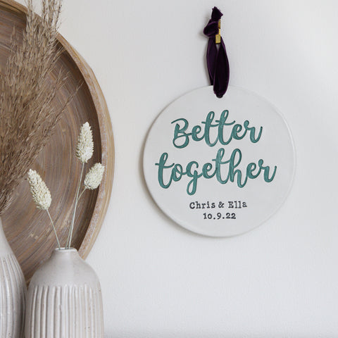 Better together scripted song lyrics on a round wall sign with the married couples names underneath, along with a special date. 