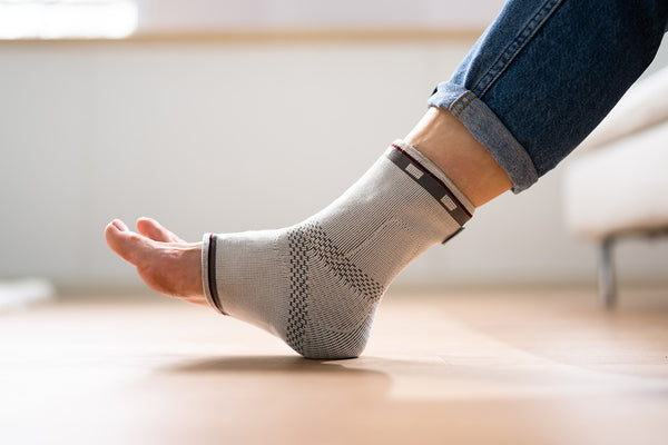 A leg wearing an ankle compression sleeve