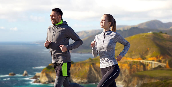 fitness, sport, people and healthy lifestyle concept - happy couple running near the coastline of california background