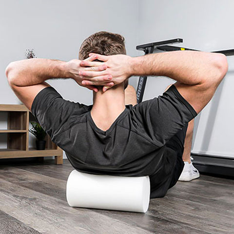 Man rolling his upper back on a small round foam with hands interwoven behind head