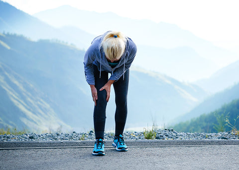 a woman in running clothes holds her injured knee