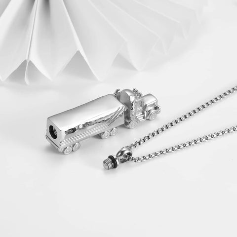 Silver semi truck urn necklace displayed on a table