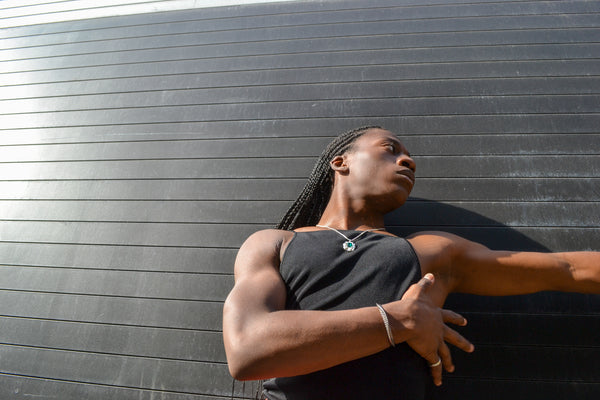 Isaiah posing outside in the Ridge Cuff and Edith Pendant Necklace