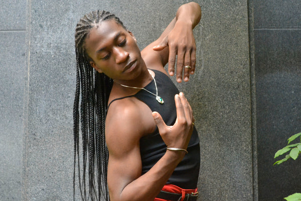 Isaiah posing outside in the Ridge Cuff and Edith pendant necklace on