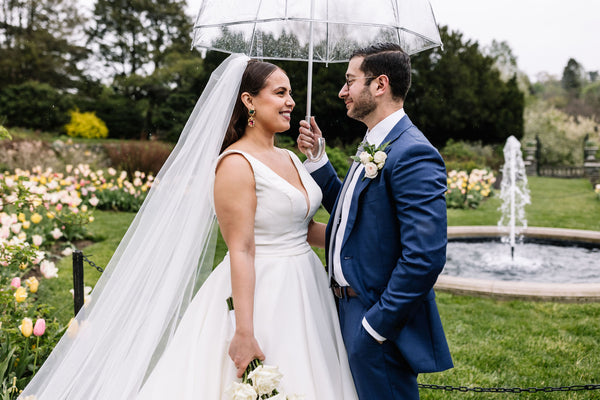 Karla and David stand under an umbrella in their wedding attire