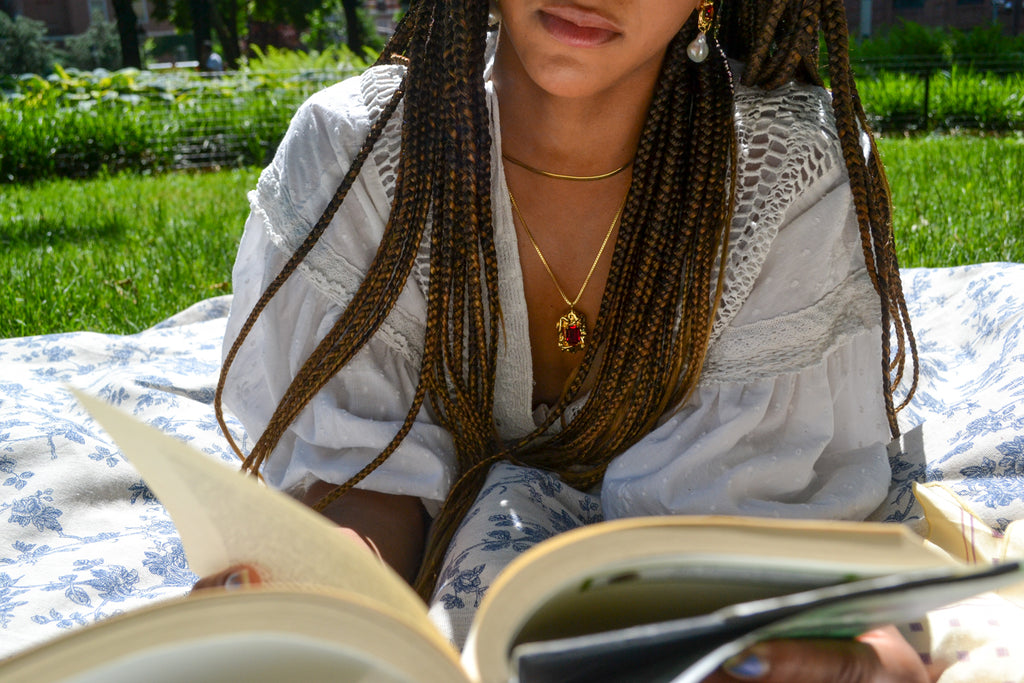Mikayla reading outside wearing the Lola Crystal Baroque Pearl Drop Earrings and the Lolita Necklace