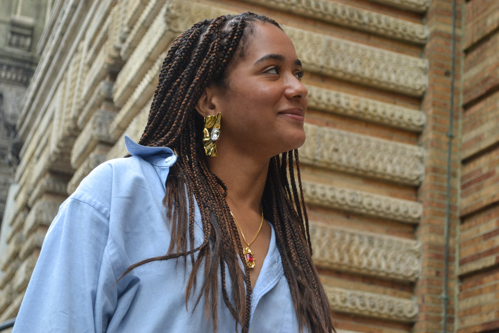 Mikayla looking to the side smiling in the Pleat Crystal Earrings 