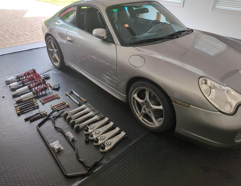 Porsche 996 in silver with new suspension parts on the floor