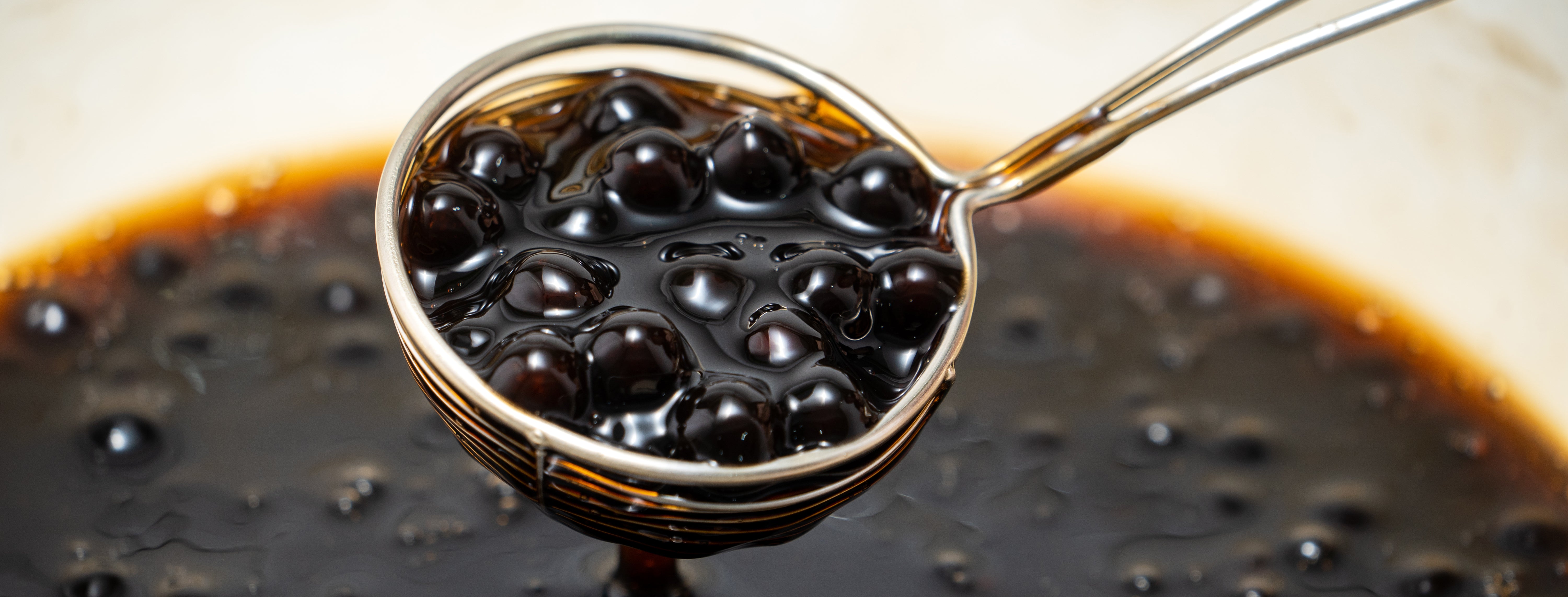 Boba or tapioca pearls in sugar syrup held up with a spoon