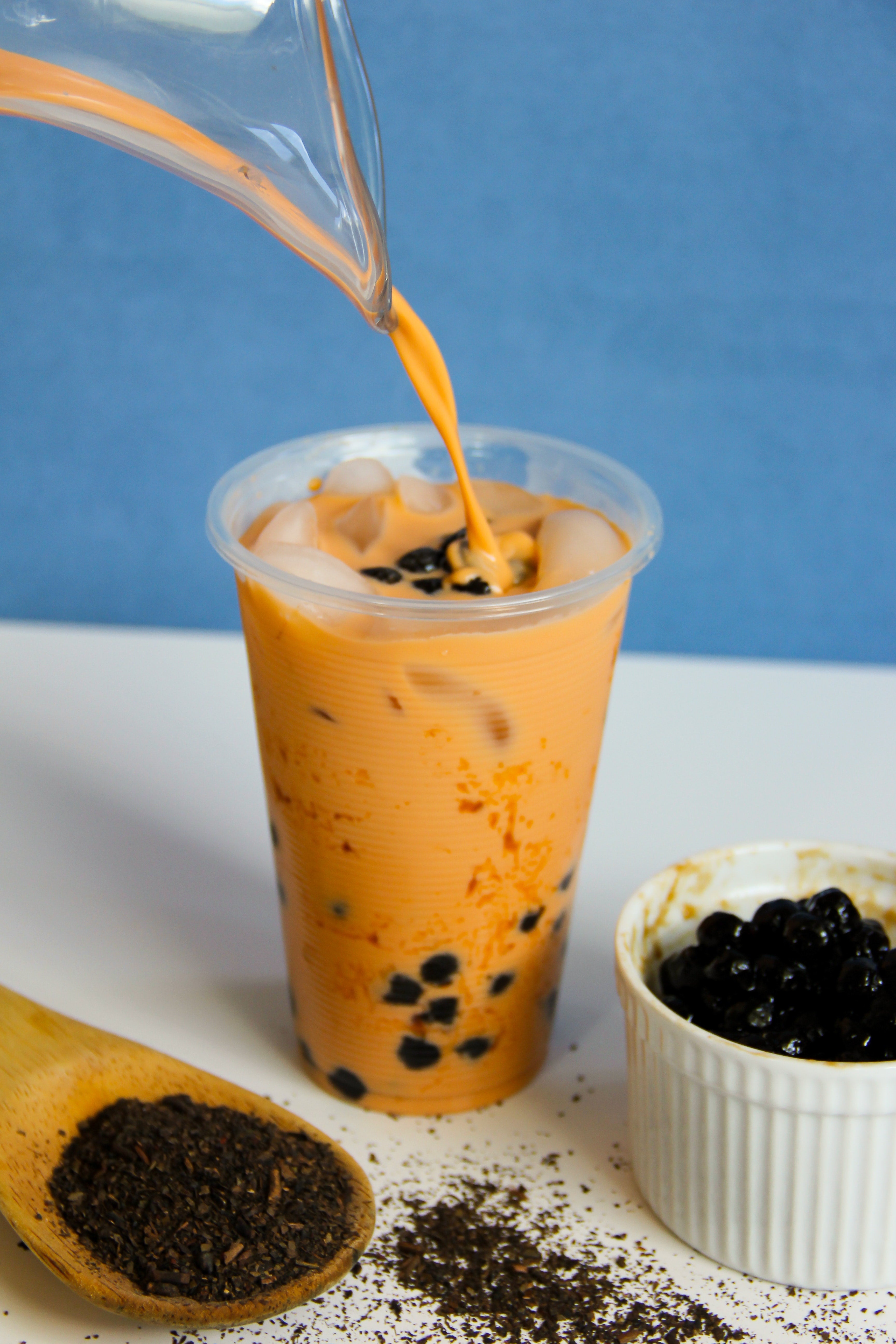 boba tea in a glass with a bowl of boba pearls 