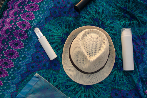 white woven hat and brandless beauty products on a floral textile