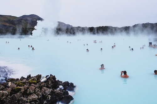 people swimming in a hot spring in the daytime