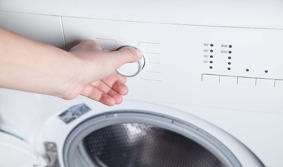 hand turning nob on a washing machine