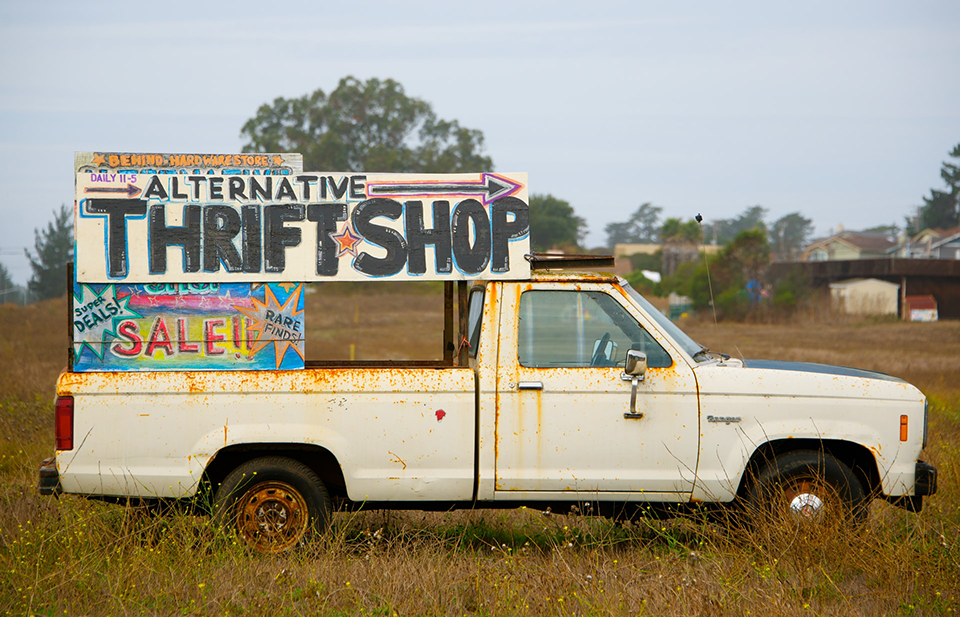 white single-cab truck with sign advertising thrift shop