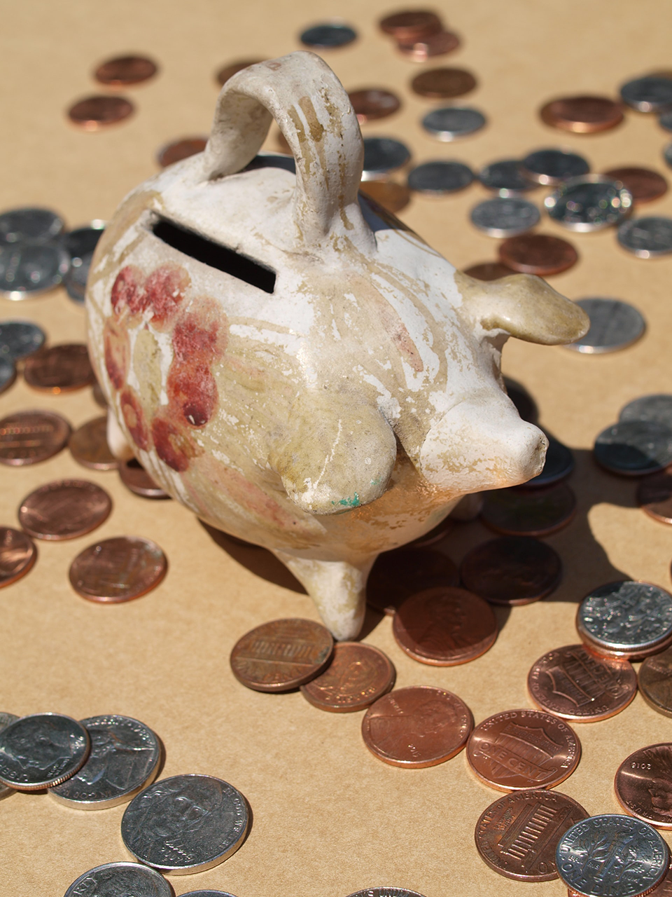 american cent coins scattered around an old ceramic piggy bank