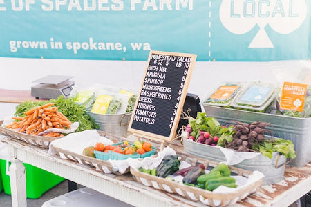 variety of vegetables and price sign on display at a farmer's market