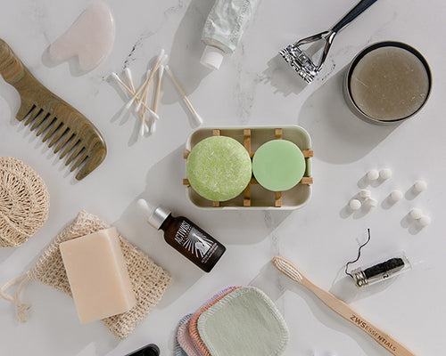 low waste everyday essentials, including shampoo and conditioner bars, bamboo toothbrush, plastic free floss, toothpaste tablets, soap bars, and bamboo cotton buds