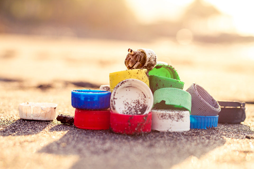 A pile of colorful plastic bottle screw tops on a beach