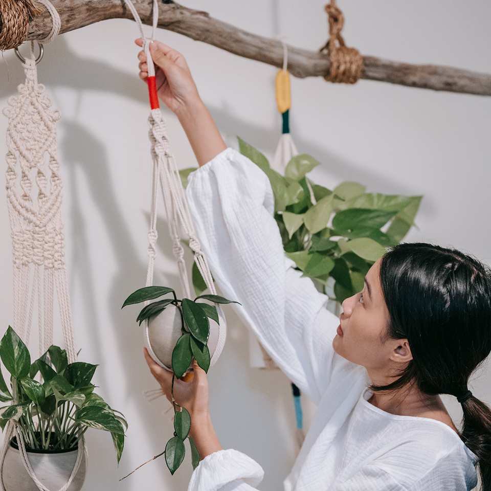 A woman adjusting a planter in a macrame hanger