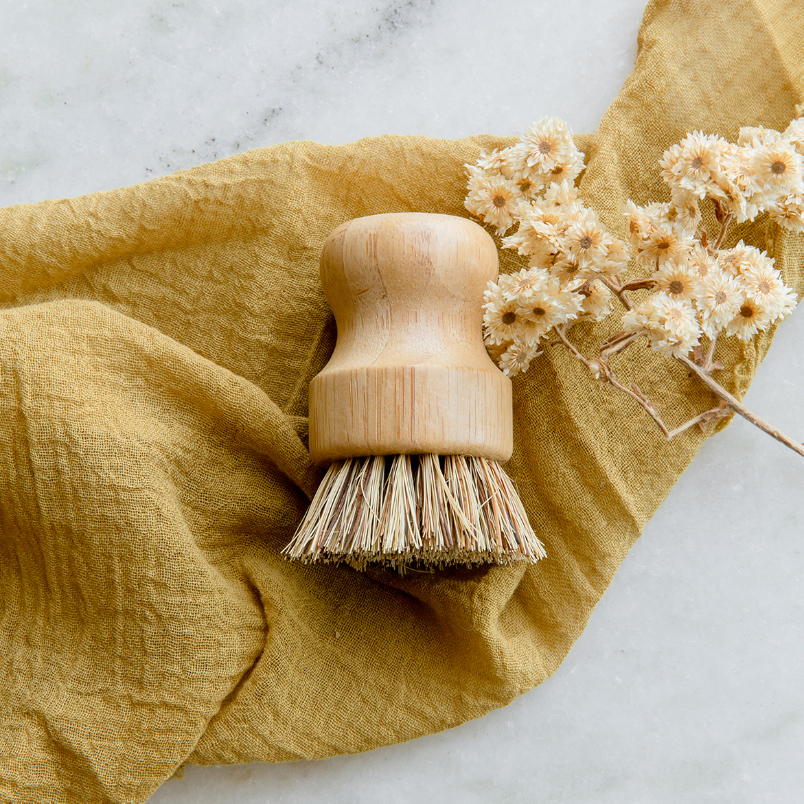 Bamboo pot scrubber with plant fiber bristles resting on tan muslin cloth