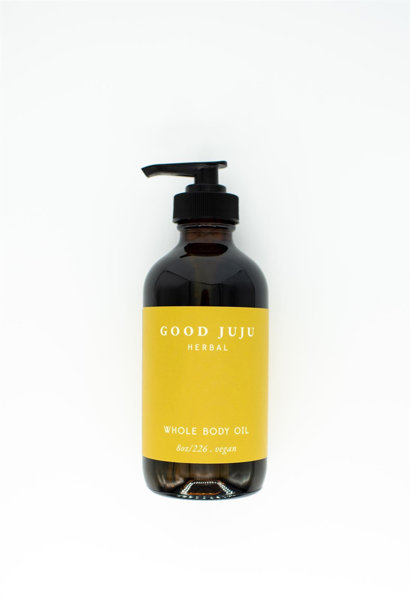 Dark Glass Jar of body oil with plastic pump lid. Yellow label reads: Good Juju Herbal Whole Body Oil