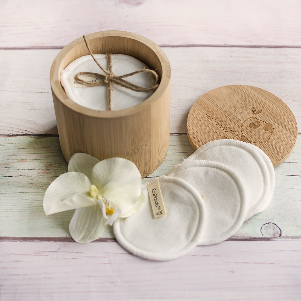 White reusable cotton rounds outside of a bamboo cotton round holder