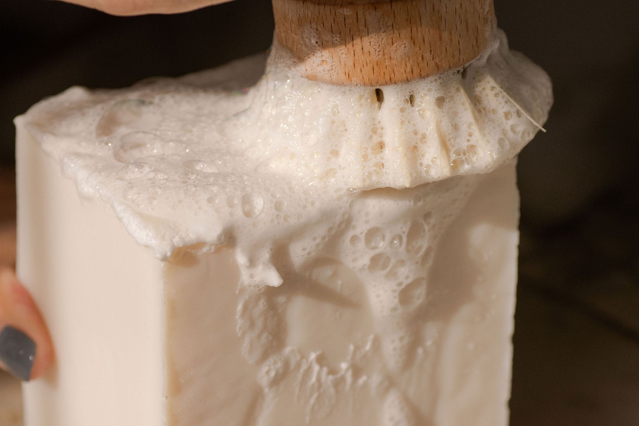 A white cube of dish soap being rubbed by a pot scrubber making bubbles