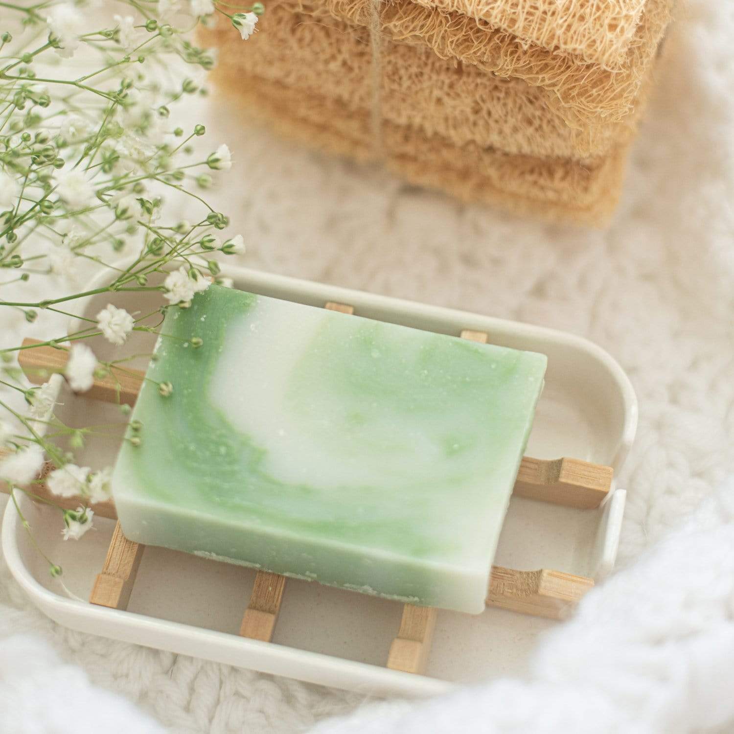 Green and white marble rectangle soap sitting in white soap dish with wood planks