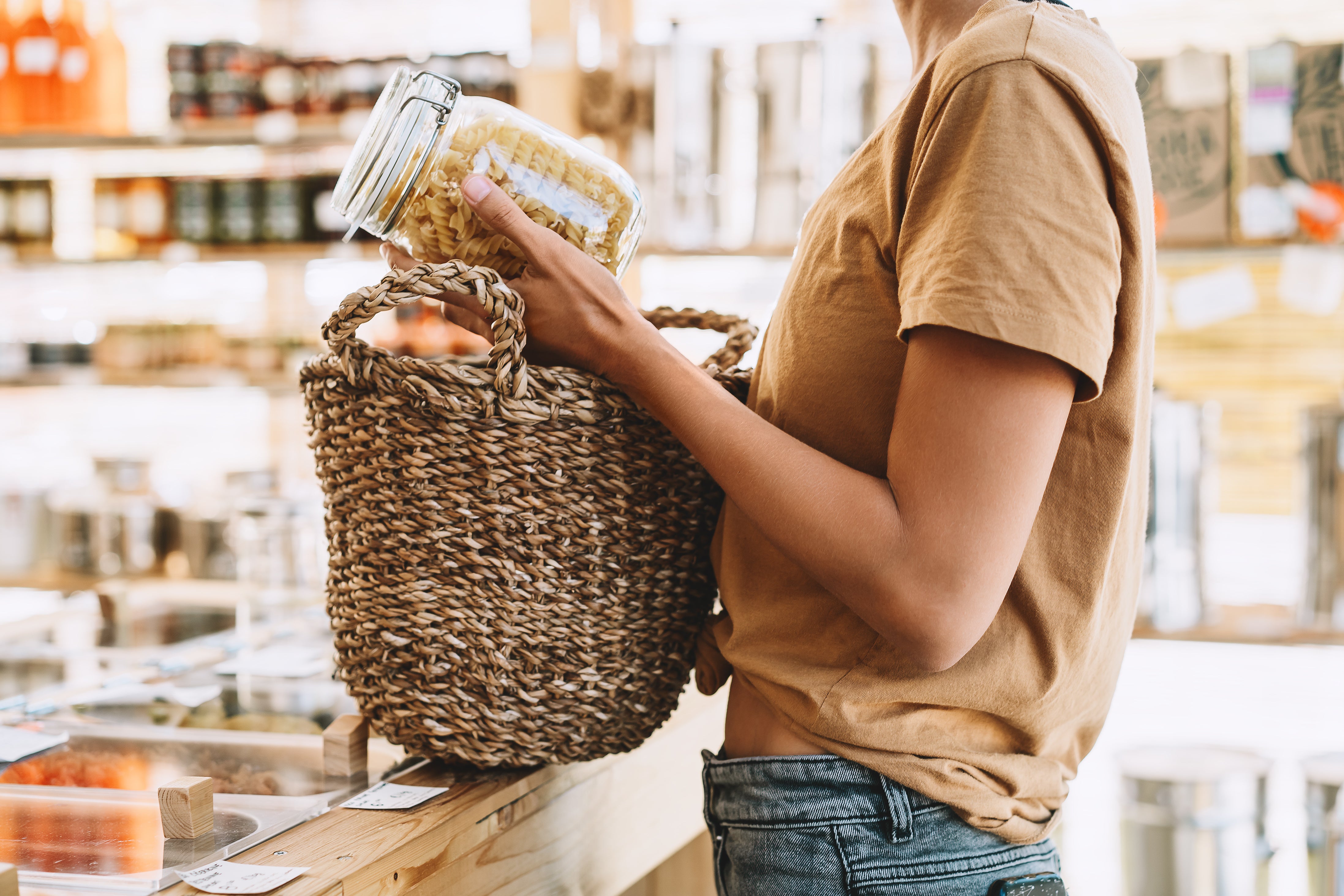 woman holding a glass jar of dry pasta at a zero waste store