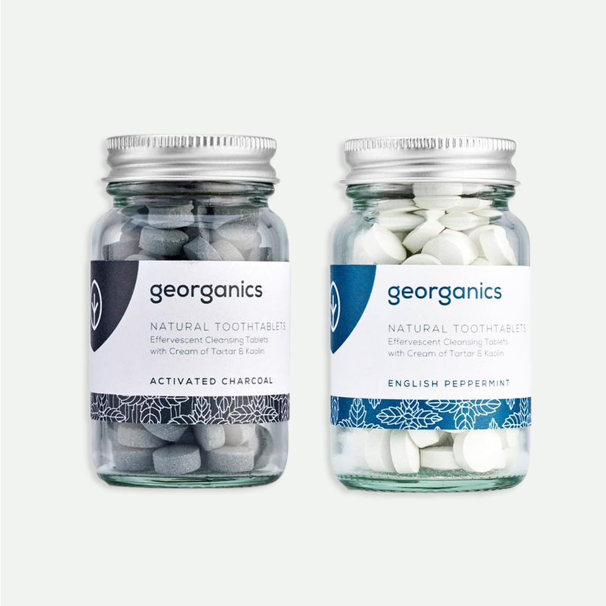 Two Georganics natural tooth tablet glass jars standing next to each other. In Activated Charcoal and English Peppermint flavors