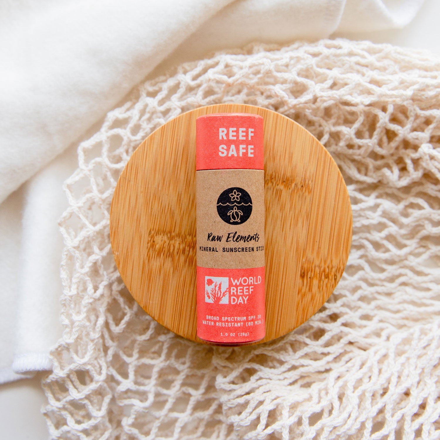 Raw Elements Reef Safe Sunscreen Stick in cardboard tube. Sitting on top of a bamboo round lid.