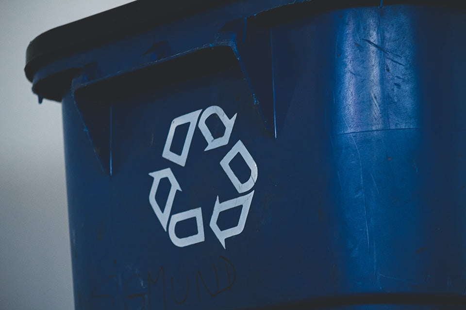 Blue bin with white recycle arrow symbol painted on the front.