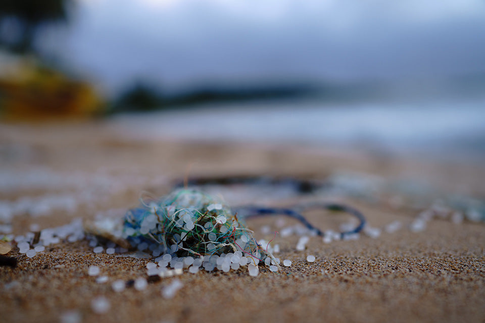 Nurdles (small beads of microplastic) wrapped up in synthetic fibers and fishing lines washed up on a beach