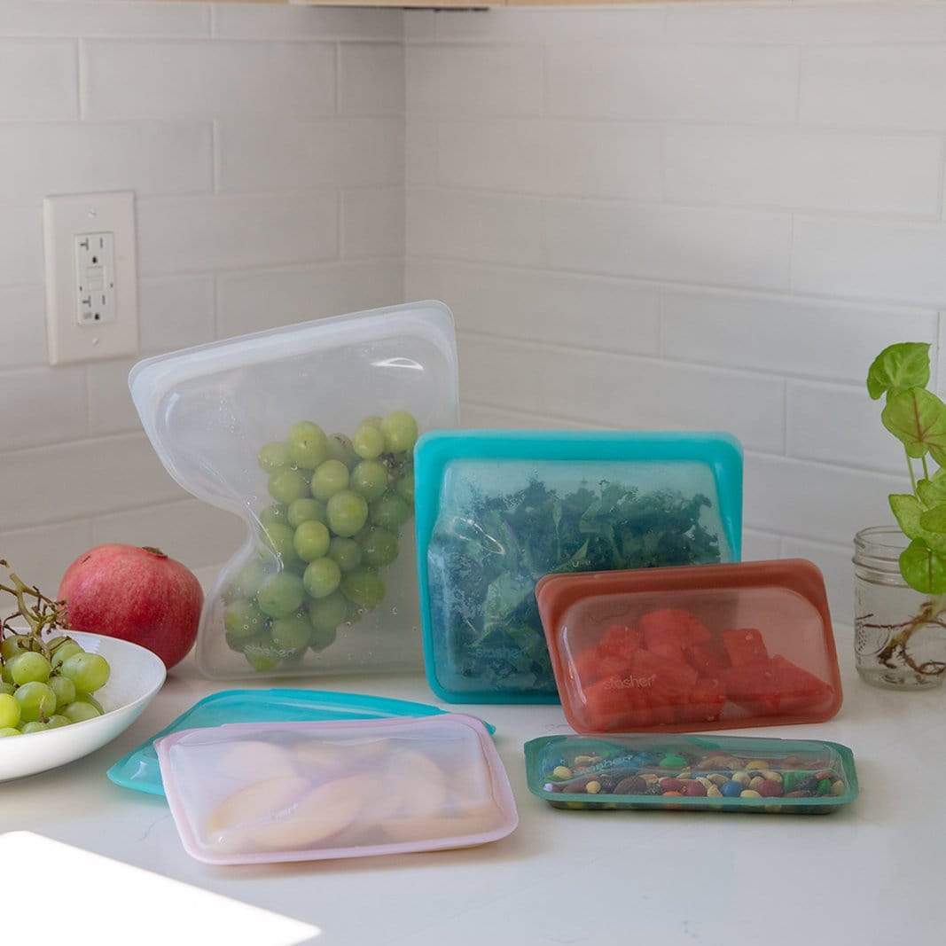 Various sizes of reusable silicone bags filled with snacks on a white kitchen counter