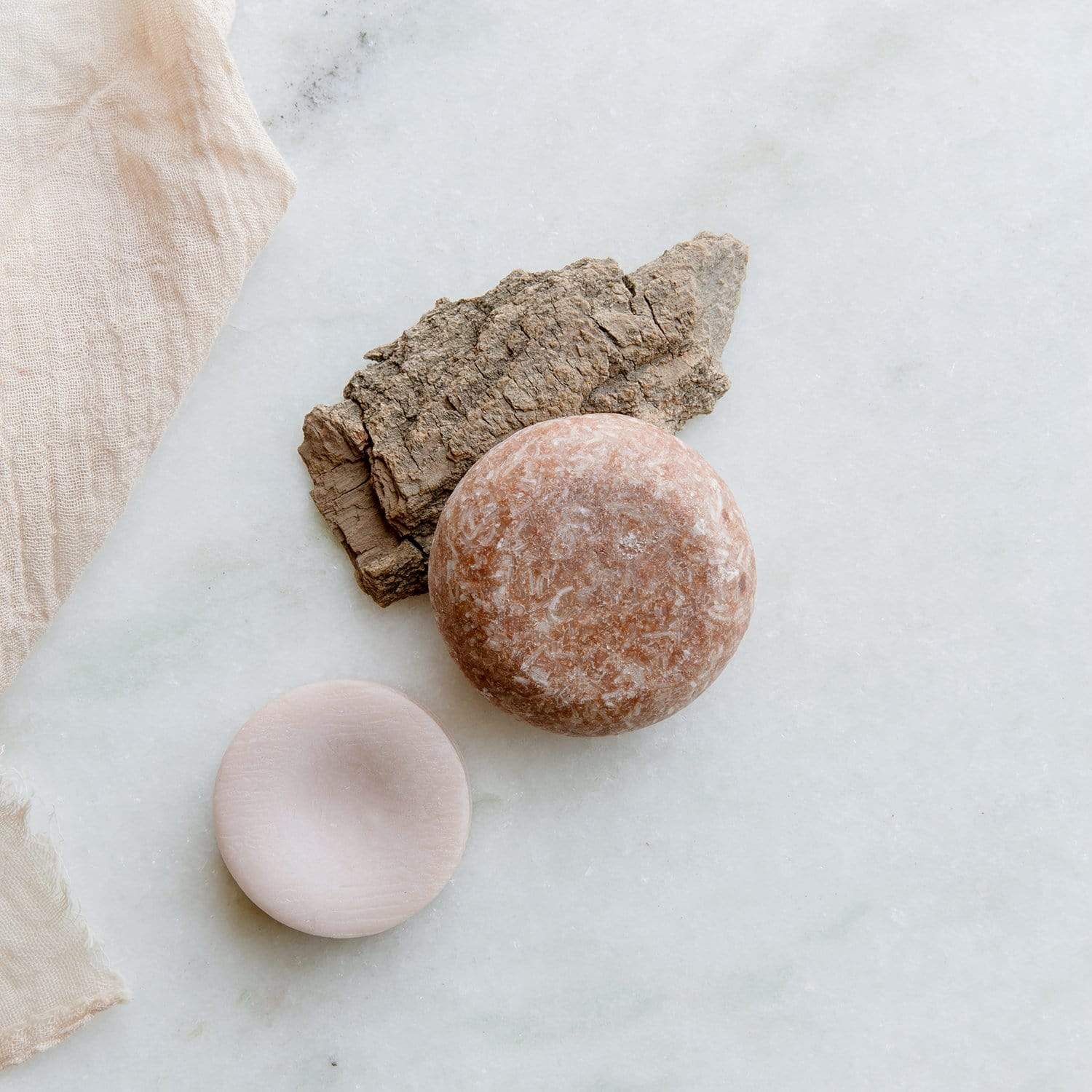 (brown) driftwood shampoo and conditioner bar resting on a zerowastestore essentials soap dish