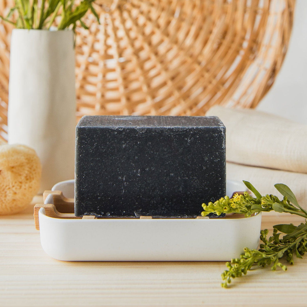 A block of black-colored soap on a white soap dish