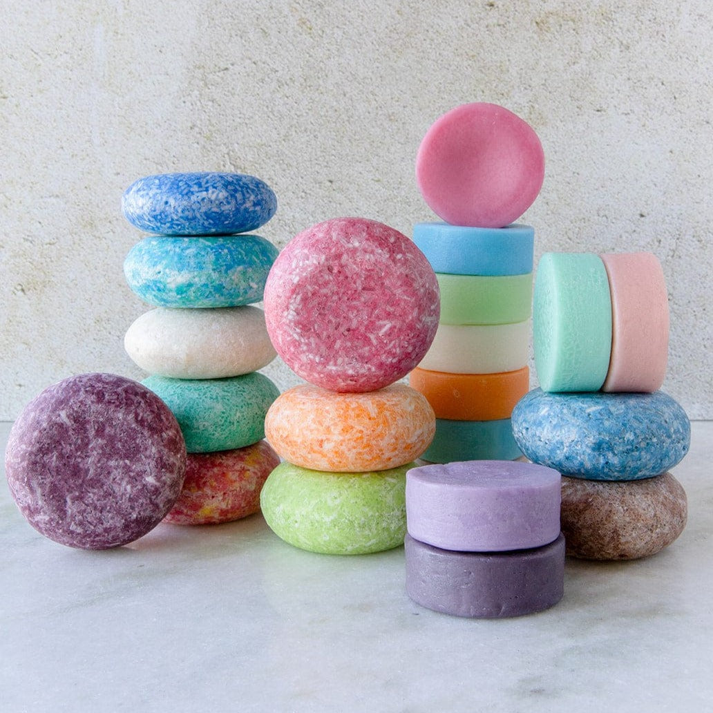 Colorful shampoo and conditioner bars stacked in columns against a marble backdrop