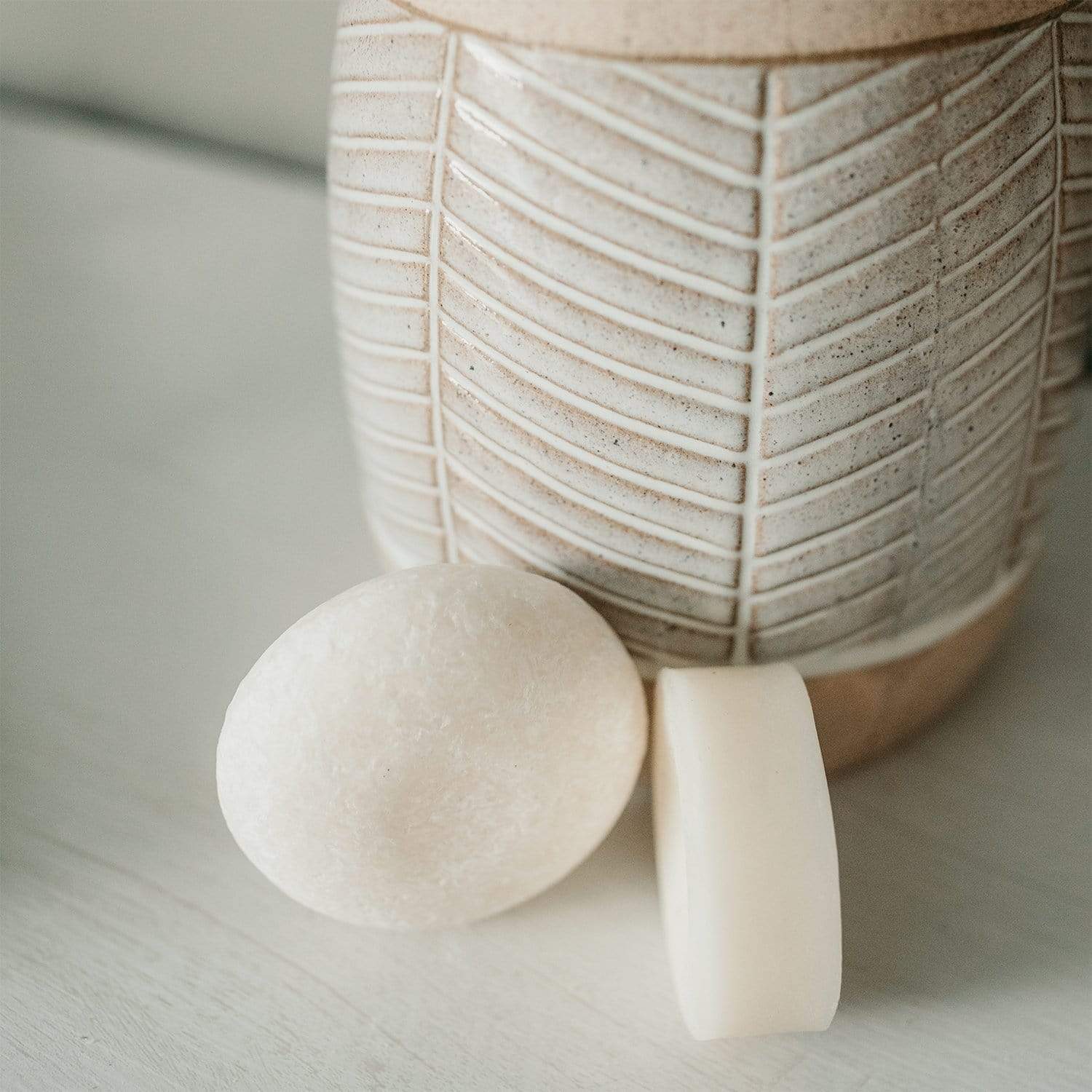 (white) simply shampoo and conditioner bars from suds & co resting against a vase