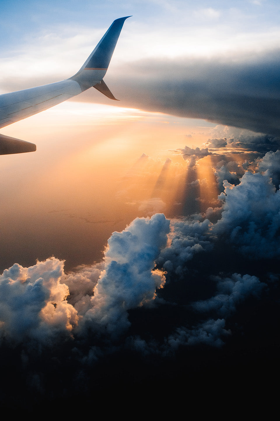 Wing of an airplane in the clouds during sunset or sunrise