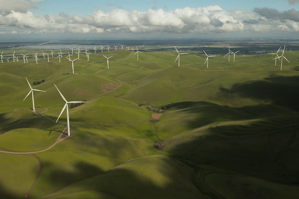 Green hills dotted with large white wind mills