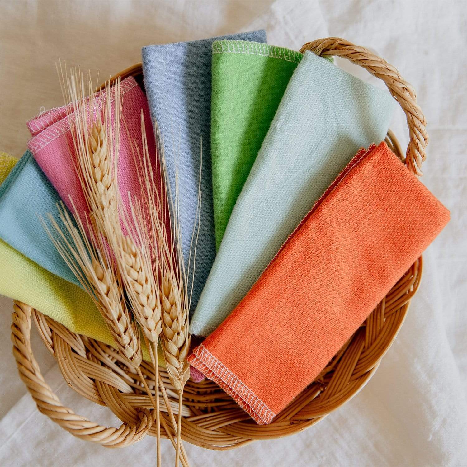 Multi-colored unpaper towels folded and placed in a woven basket