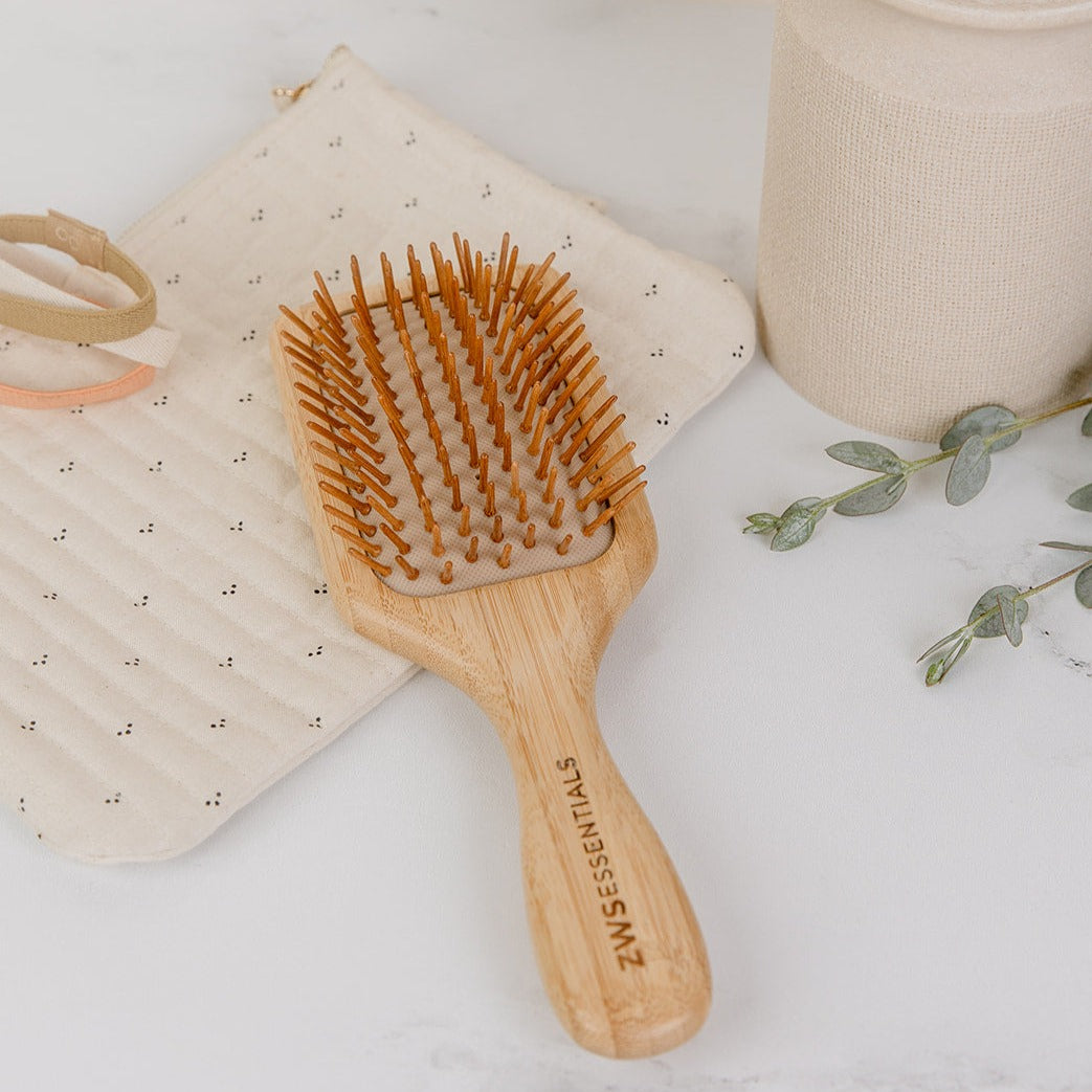 Brush with bamboo brush on top of a linen blanket. Upper label/sticker reads #1 bestseller, 5 stars.